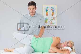 Handsome physiotherapist manipulating patients leg