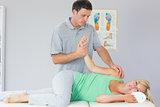 Handsome physiotherapist manipulating patients arm