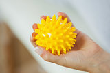 Close up of female left hand holding yellow massage ball