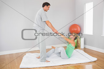 Content physiotherapist helping patient doing exercise