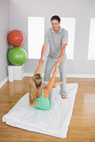 Smiling physiotherapist helping patient doing exercise