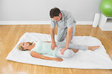 Physiotherapist treating patient on a mat on the floor