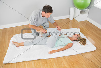 Physiotherapist treating patients leg on a mat on the floor