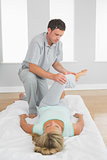 Physiotherapist examining patients leg on a mat on the floor