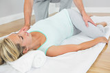 Physiotherapist checking patients hips on a mat on the floor