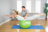 Physiotherapist helping patient doing exercise with exercise ball