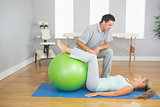 Physiotherapist checking patient doing exercise with exercise ball