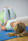 Blonde woman lying on floor doing exercise with exercise ball