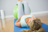 Blonde woman doing exercise with exercise ball on the floor