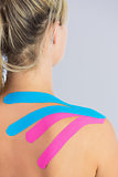Close up of patients shoulder with applied pink and blue kinesio tape