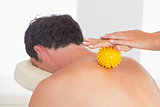 Physiotherapist massaging male patient with yellow massage ball