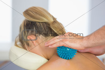 Physiotherapist massaging female patient with blue massage ball