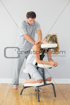 Masseur treating clients back in massage chair