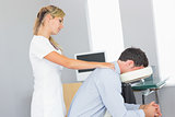 Masseuse treating shoulders of client in massage chair