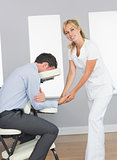 Masseuse massaging clients hand in massage chair