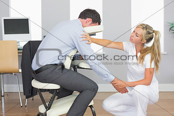 Masseuse treating clients arm in massage chair