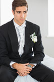 Young handsome bridegroom sitting on bed