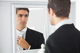 Serious handsome bridegroom looking in mirror