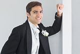 Handsome bridegroom leaning against a wall