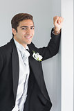 Cheerful young bridegroom leaning against wall