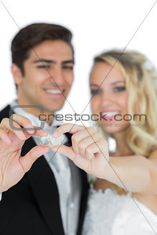 Smiling young married couple holding their wedding rings