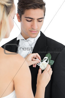 Young bride pinning a flower on her husbands suit