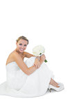Beautiful young bride sitting on floor holding a bouquet