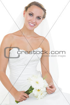 Lovely bride sitting on ground holding a bouquet