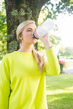 Fit calm blonde drinking from sports bottle