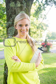 Fit smiling blonde holding sports bottle
