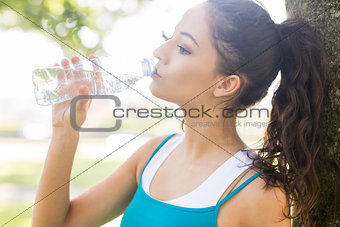 Active calm brunette drinking from a water bottle