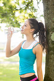 Active pretty brunette drinking from a water bottle