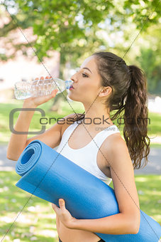 Active calm brunette holding exercise mat