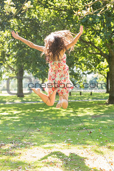 Rear view of attractive stylish brunette jumping in the air