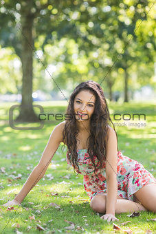 Stylish cheerful brunette sitting on grass