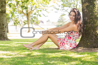 Stylish pretty brunette sitting under a tree