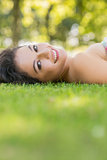Stylish cheerful brunette lying on a lawn