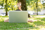 Brunette lying on the grass typing at her laptop