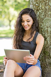 Casual smiling brunette sitting using tablet