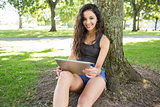 Casual happy brunette sitting holding tablet