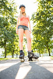Casual smiling blonde standing in inline skates on pathway