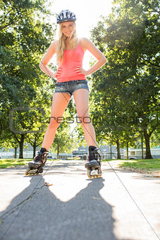 Casual smiling blonde standing hands on hips wearing inline skates