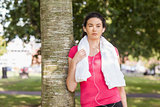 Young sporty woman leaning against a tree
