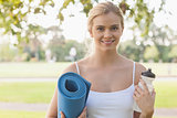 Cheerful blonde woman posing holding an exercise mat
