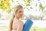 Beautiful sporty woman posing holding an exercise mat