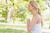 Side view of peaceful young woman meditating sitting in park