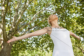Low angle view of young woman doing yoga spreading her arms