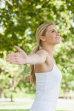 Side view of cheerful attractive woman doing yoga spreading her arms