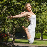 Side view of young fit woman jumping spreading her arms