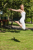 Side view of young cheerful woman jumping spreading her arms